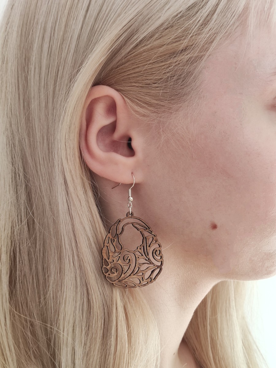 Kolczyki ażurowe z drewna lekkie i wiszące, zbliżenie na ucho i kolczyk.
